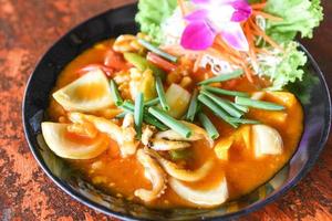 Stir fried squid with salted egg yolk on white dish on table background, curry squid photo