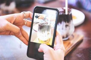 Food photography woman hands make photo cocoa drink and cake with smartphone - taking photo food for post and share on social networks with camera smart phone in restaurant