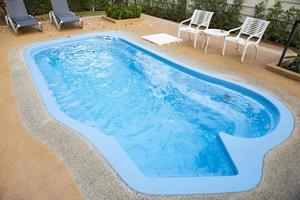 Backyard area with swimming pool blue water and tables chairs and trees fenced background , swimming pool garden photo