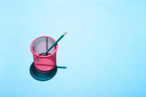 Minimal still life image of a mesh pink pencil cup on blue background. photo