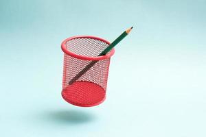 Flying red mesh pencil cup with a single pencil. Green pencil in a flying cup. photo