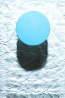 Round blue object on abstract blue background. Minimalist flat lay single object with shadow. photo