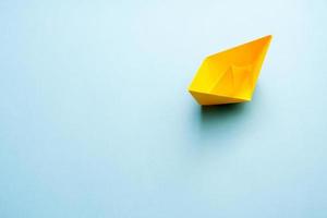 Yellow paper boat on blue background with free copy space for text. photo