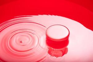 Abstract red shiny surface with a round object. Water in water. Abstract red background. photo