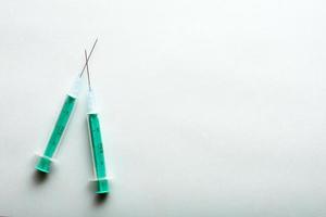 A pair of medical syringes on blue background with free copy paste space for text. photo