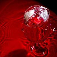 Close up image of water splashes in a glass on red background. photo