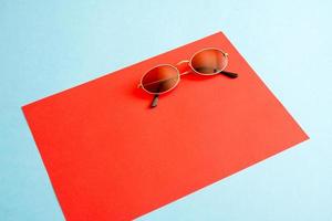 Simple flat lay sunglasses on red paper background. photo