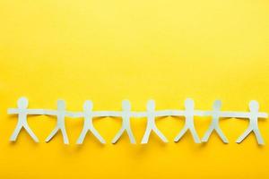 Light blue paper people on yellow background. Friendship flatlay concept. photo