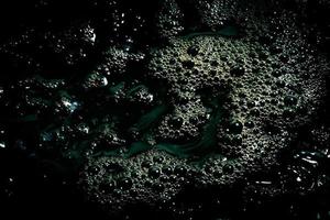 Black water surface with bubbles. Dark liquid background. photo