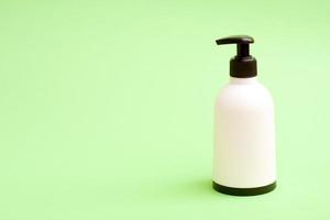 White plastic soap bottle with blat top and bottom on green background with free copy paste space for text. photo
