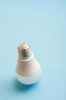 White light bulb standing upside down on blue background. photo