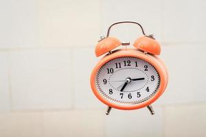 Retro style orange alarm clock flying in the bathroom. photo