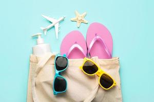 Summer holiday concept.Top view of beach bag with flip flops,sunglasses,sunscreen,airplane and starfish photo