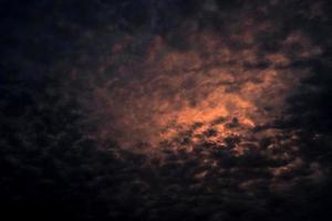 Red light of sun in dark cloudy sunset sky. Dramatic sky with beautiful pattern of fluffy clouds. Mental power or psychic power background. Power of nature. Exotic cloudscape. Climate change concept. photo