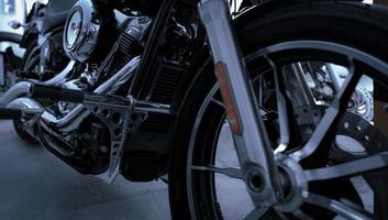 Selective focus on motorcycle frame. Closeup motorcycle exhaust pipe, engine guard, and foot rest. Motorcycle industry. Shiny chrome motorbike engine. Vintage motorbike. Blur aluminum alloy wheel. photo