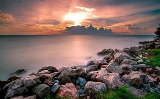 Rocks on stone beach at sunset. Beautiful landscape of calm sea. Tropical sea at dusk. Dramatic golden sunset sky and clouds. Beauty in nature. Tranquil and peaceful concept. Clean beach in Thailand. photo