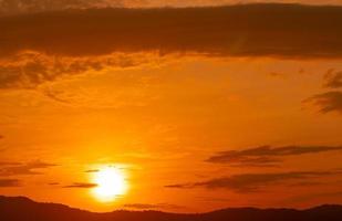 hermoso cielo naranja al atardecer y nubes sobre el bosque. cielo crepuscular fondo de la naturaleza. vista majestuosa. fondo abstracto de paz y relajación. gran sol dorado en la noche. paisaje nuboso al atardecer. foto