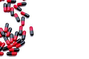 Red-black capsule pills spread on white background. Antibiotic drug use with reasonable. Pharmaceutical industry. Pharmacy background. Global healthcare. Pile of capsule pills with copy space. photo