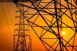 High voltage electric pole and transmission lines in the evening. Electricity pylons at sunset. Power and energy. Energy conservation. High voltage grid tower with wire cable at distribution station. photo