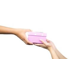 Closeup hands giving and receiving pink gift box isolated on white background photo