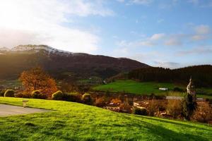 Sunrise shine on green grass field at public park at the hill near city in valley. Beautiful landscape in Europe. City near the mountain with clean environment. Sustainable city. Europe travel concept photo