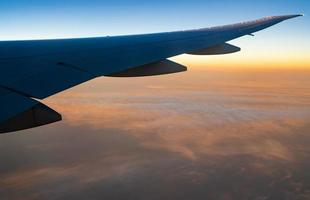 Wing of plane over white clouds. Airplane flying on sunrise sky. Scenic view from airplane window. Commercial airline flight. Plane wing above clouds. Flight mechanics concept. International flight. photo