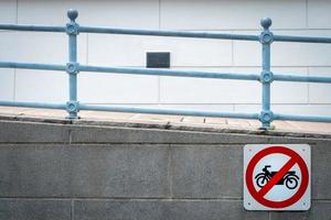 Motorcycle no entry sign install in front of tunnel under the road. Traffic sign to prohibit motorcycle. Restrictive signs. Ramp and iron rail. Motorcycle caution and stop driving to this way. photo