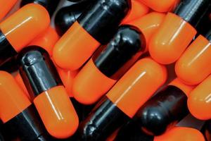 Top view of orange, black antibiotic capsule pills. Pharmaceutical industry. Drug production. Pharmacy drugstore background. Global healthcare. Antibiotic drug resistance concept. Antimicrobial pills photo