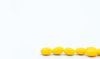 Yellow sugar coated tablets pills on white background with copy space. Medicine for treatment constipation. photo