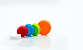 Macro shot detail of different size of white, green, red, blue and orange color round plastic screw caps on white background and copy space. photo