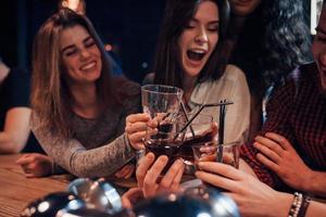 beber whisky grupo de jóvenes amigos sonriendo y haciendo un brindis en la discoteca foto