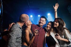 Spontaneous kiss. Beautiful youth have party together with alcohol in the nightclub photo