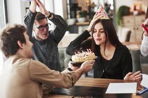 Blowing candles. One of employees have birthday today. Friendly coworkers decides to make surprise for her photo