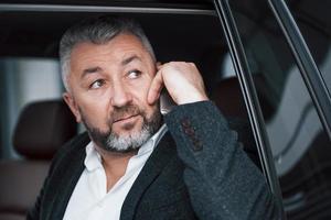 Warns employees that he will late due to traffic jams. Business talk in the car while stopped. Having conversation about new deals photo