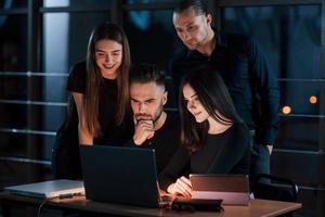 Thoughtful look. Team of young business people works on their project at night time in the office photo