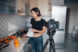 cámara frente a la mujer. chica en la cocina moderna de casa a la hora del fin de semana por la mañana foto