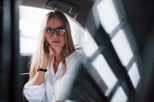 ansiedad en su rostro. mujer de negocios inteligente se sienta en el asiento trasero del coche de lujo con interior negro foto