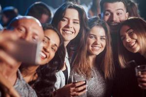 Such positive nice people. Friends taking selfie in beautiful nightclub. With drinks in the hands photo