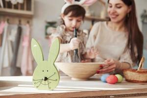 Close up view of the rabbit face. Mother and daughter in bunny ears at easter time have some fun in the kitchen at daytime photo