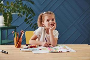 buen retrato linda niña en la escuela de arte dibuja sus primeras pinturas con lápices y marcadores foto