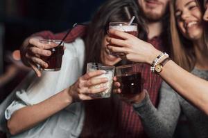 fiesta con alcohol. grupo de jóvenes amigos sonriendo y haciendo un brindis en la discoteca foto