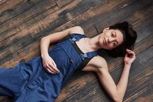 vista superior. la chica del uniforme azul para el trabajo está tumbada en el suelo de madera relajándose foto