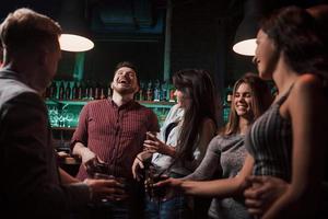 Guy tells a joke and laughs hard. Beautiful youth have party together with alcohol in the nightclub photo