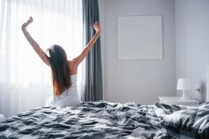 estado de ánimo impresionante. una mujer muy joven sentada en la cama a la mañana en su habitación foto