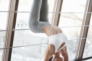 Cropped photo. Warming up and doing stretches near the window with handrails at the gym photo