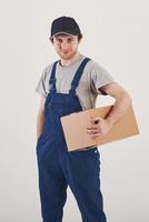 Your order is here. Guy with box in hands stands against white background in the studio photo