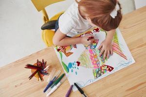 Process of making art. Cute little girl in art school draws her first paintings by pencils and markers photo