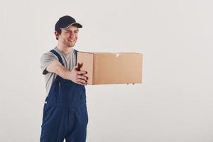 Giving the order. Guy with box in hands stands against white background in the studio photo