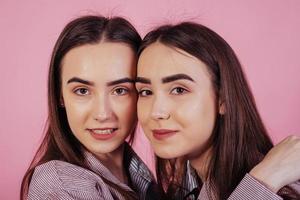 Cute close up portrait. Two sisters twins standing and posing in the studio with white background photo