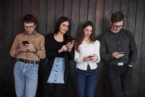 Youth stands against black wooden wall. Group of friends spending time together photo